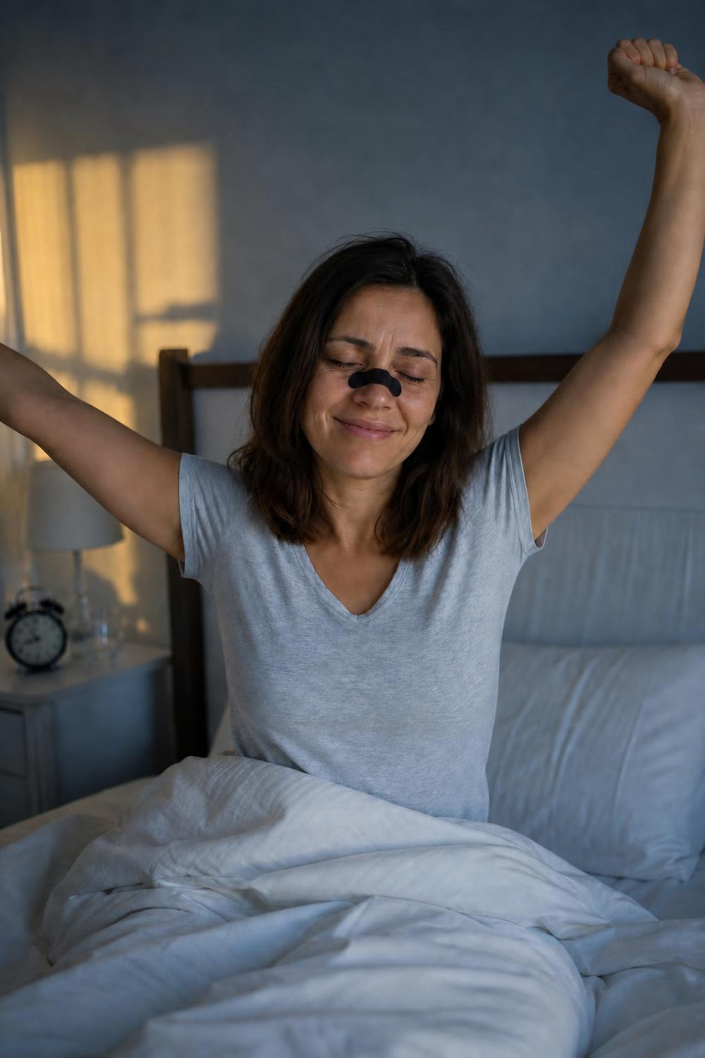 La misma mujer, descansada, estirándose en la cama con una tira nasal